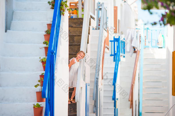 美丽的女孩在典型的希腊传统村庄的街道上，迈科诺斯有惊人的台阶和白色的墙壁
