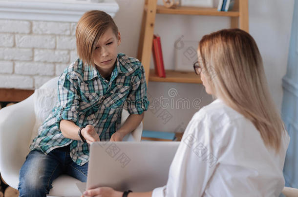 愤怒的男孩在访问心理学家时指着笔记本电脑屏幕