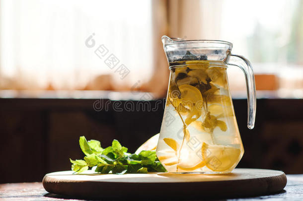 新鲜柠檬水在罐子与黄色柠檬和薄荷在木制厨房背景。 水排毒。