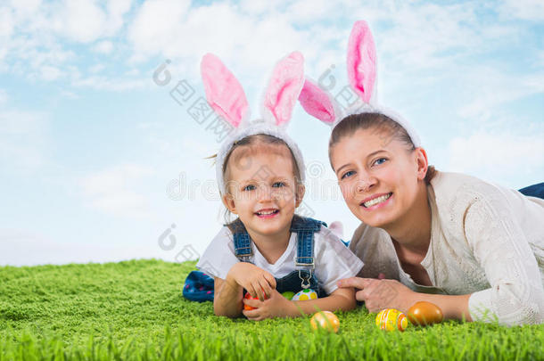 复活节<strong>兔子</strong>。 小<strong>女孩</strong>和妈妈穿着复活节<strong>兔子</strong>躺在草地上
