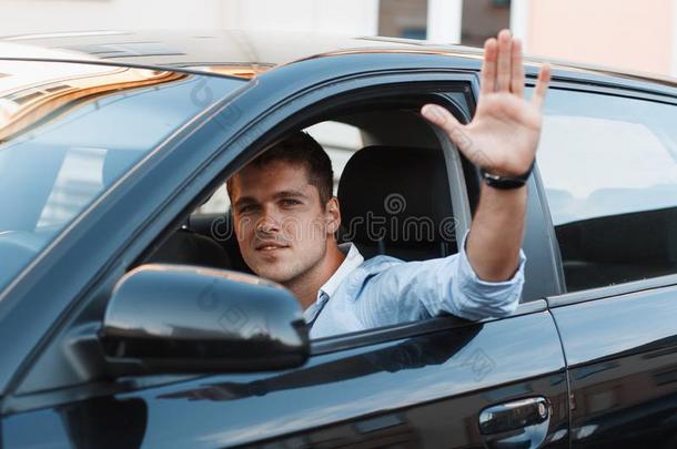 一位坐在车里的年轻人把手伸出窗外。 男人同意