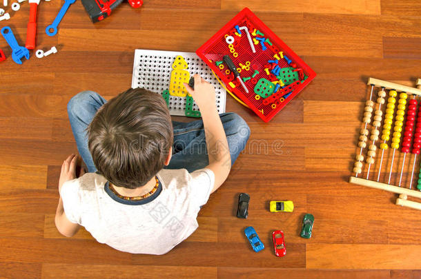 孩子在房间里坐在地板上玩玩具工具箱。顶部视图
