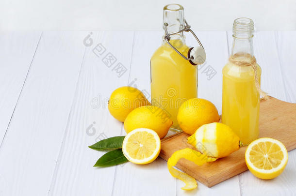 新鲜挤压柠檬汁在瓶子和柠檬的轻背景。 用于维生素饮料或鸡尾酒。