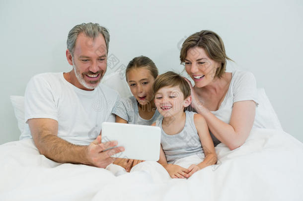 家庭在卧室的床上使用数字平板电脑