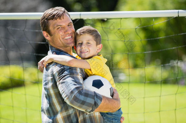 父亲和儿子在阳光明媚的日子里在公园里<strong>踢</strong>足球