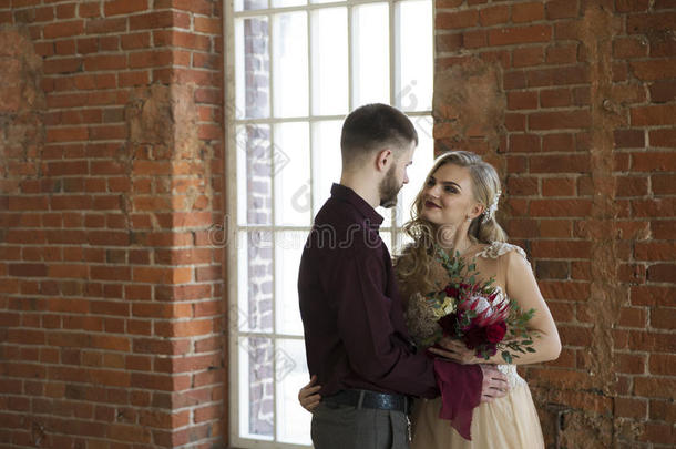 新娘和新郎的姿势靠近窗户和老式砖墙