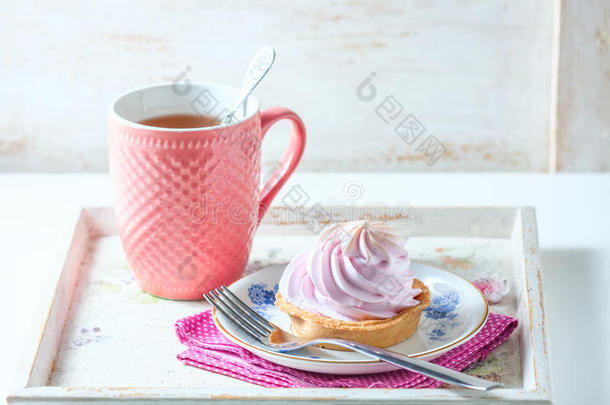美丽美味的早餐概念。 在老式的服务托盘上有奶油蛋糕和一杯茶。