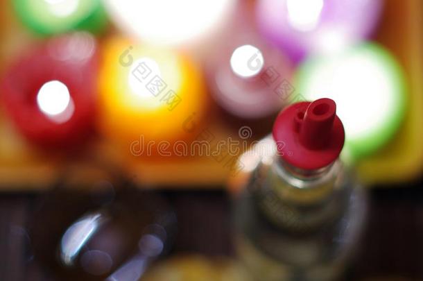 一瓶带有塑料水壶的白酒的抽象图像。 一个切碎的橙色和模糊的彩色燃烧蜡烛背景。