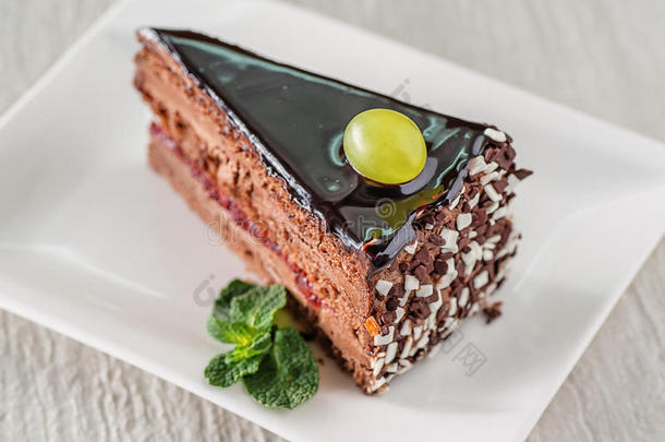 巧克力奶油蛋糕与深色顶部和新鲜葡萄在顶部，产品摄影的糕点
