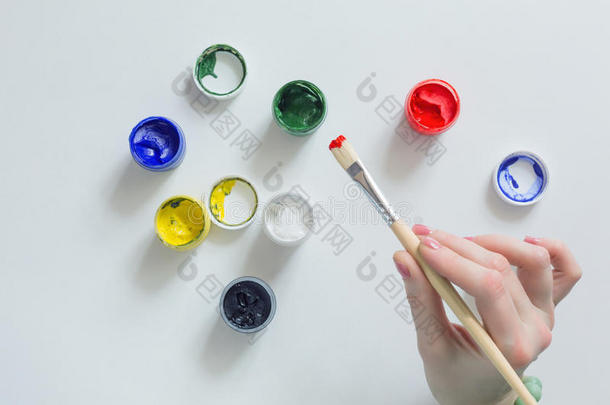 艺术家手拿刷子和彩色油漆在白色桌子上