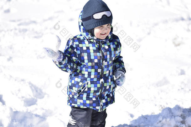 可爱的男孩穿着暖和的衣服，在美丽的冬天下雪的日子在冬天的森林里玩耍