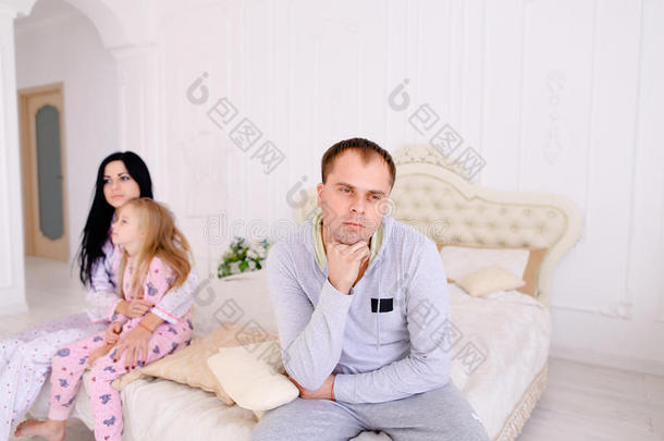 夫妻争吵和孩子心烦意乱，坐在白色的室内床上