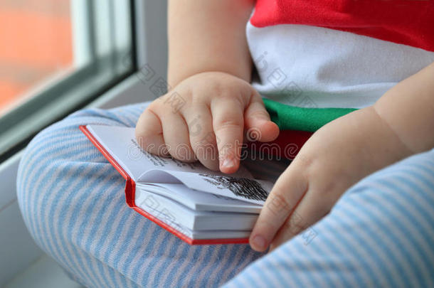 小男孩在读一本书，双手紧握着书页