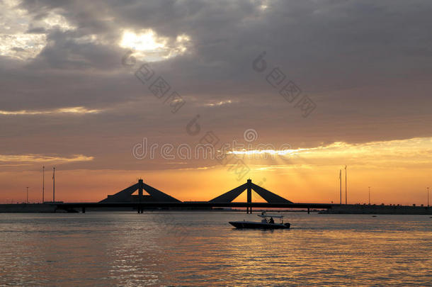 日落时，一艘船在背景处与谢赫·伊萨·本·萨尔曼·蔡韦桥一起航行