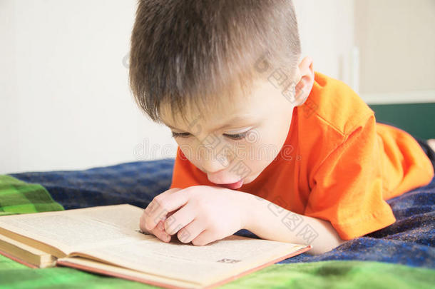 儿童教育，男孩躺在床上看书，带书的儿童肖像，有趣的故事书