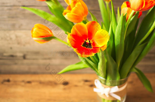 棕色木制背景上花瓶里漂亮的橙色郁金香。 对可爱的女士<strong>来</strong>说是理想的<strong>春</strong>天心情。