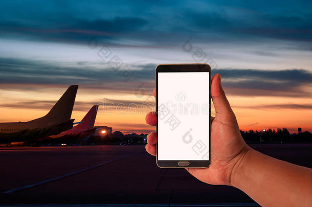 人的手拿着手机在模糊的飞机上停车，在黄昏的天空时期