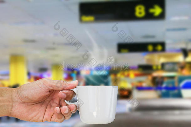 手拿着热咖啡杯在机场模糊的<strong>候机</strong>厅