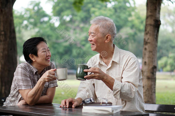 亚洲老年夫妇阅读书籍，学习投资和饮料