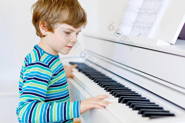 漂亮的小男孩在客厅或<strong>音乐学校</strong>弹钢琴