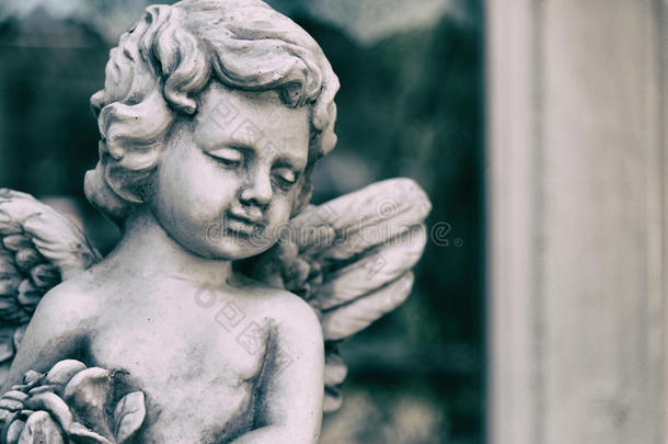 美丽的<strong>丘比特</strong>天使雕像在复古花园在夏天。 手里拿着花束