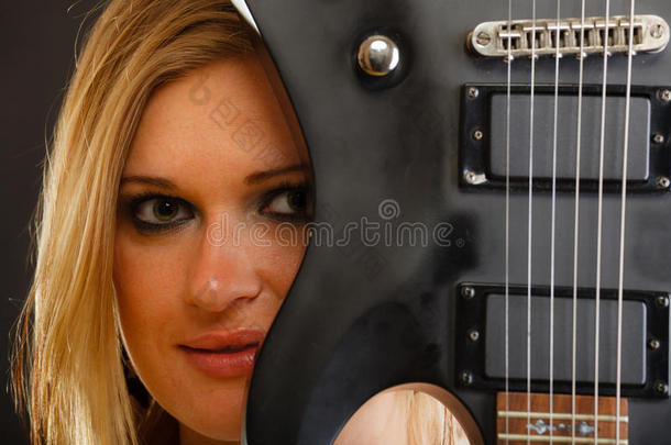 金发女子手持电吉他，黑色背景