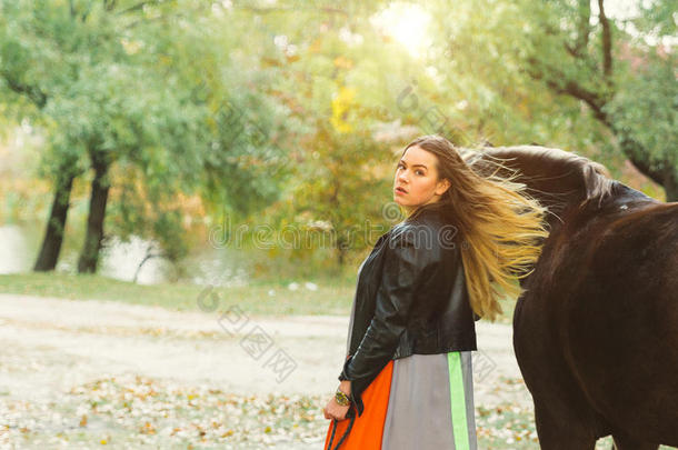 一个漂亮的女孩正在遛马。专注于那个女孩。图像的暖色调。柔和的焦点。