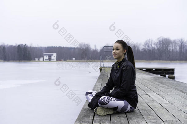 美丽的瑞典高加索人健身少女坐在木桥上户外冬季景观