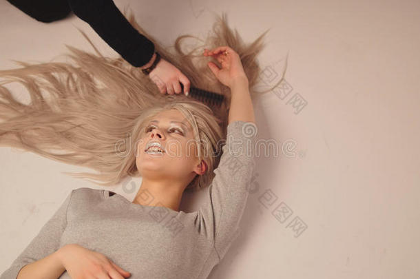 金发模特女孩躺在摄影棚-摄影师梳理模特的头发，顶部视图