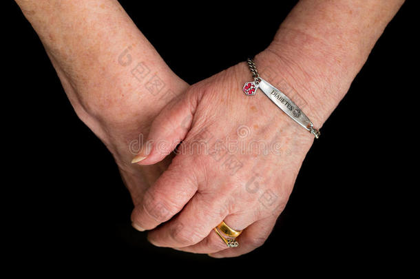 老年妇女`手拿着糖尿病的医疗警报手镯。