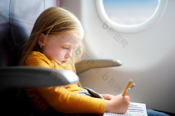 可爱的小女孩乘飞机旅行。 孩子坐在飞机窗口，用毛毡笔画一幅画。