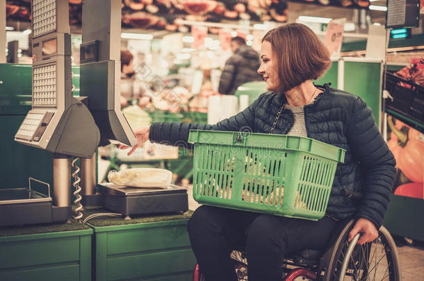 残疾妇女在轮椅上靠近秤在商店