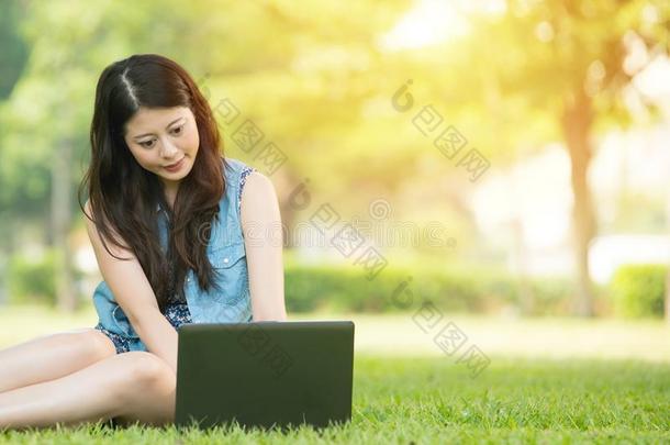 美丽的亚洲女人在户外公园使用电脑
