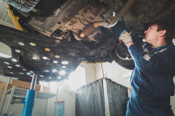 汽车服务-工人机械师检查汽车底部