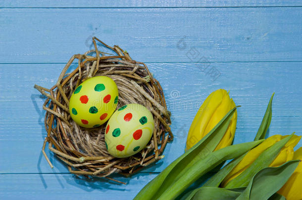 鸟巢里的复活节彩蛋画鸡蛋。 一束黄色郁金香