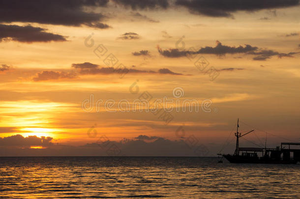 船的轮廓穿过海洋，走向地平线上橙色的日落天空。