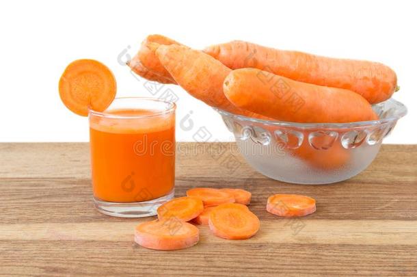 新鲜胡萝卜汁在玻璃，切片和胡萝卜蔬菜在碗在木桌上，白色背景。