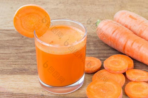 新鲜<strong>胡萝卜</strong>汁在玻璃和<strong>切片胡萝卜</strong>蔬菜在木桌上。