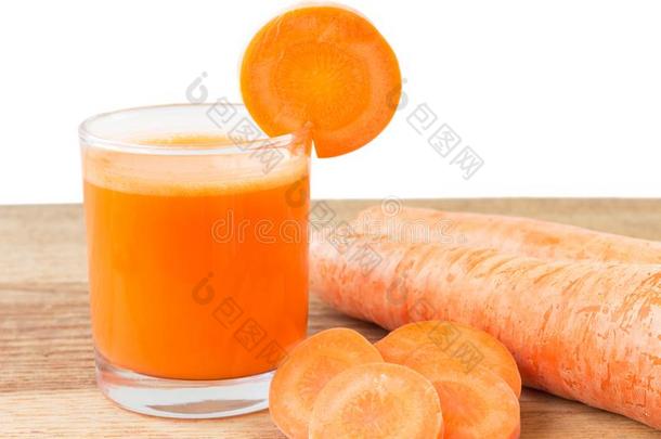 新鲜胡萝卜汁在玻璃和切片胡萝卜蔬菜在木桌上，白色背景。