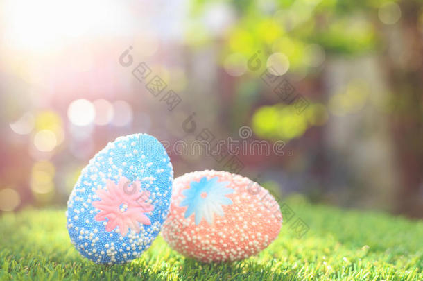 绿色草地上的彩色鸡蛋与模糊的Bokeh和阳光背景。 复活节使用