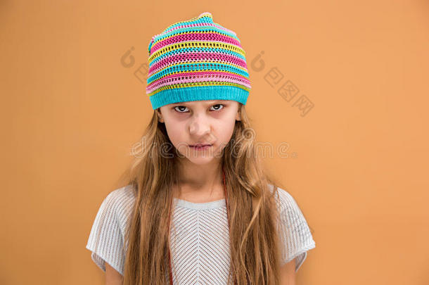 愤怒的年轻女孩戴着帽子，恨恨地看着相机