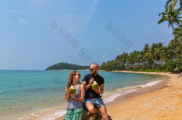 一对夫妇在海滩上喝椰子汁