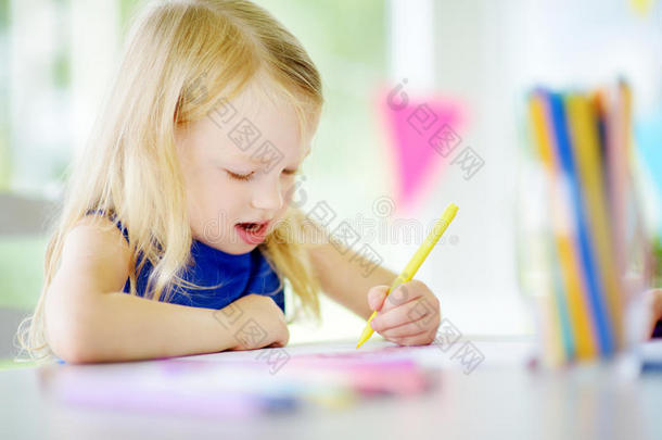 可爱的小女孩在托儿所用彩色铅笔画画。 学校里有创意的孩子绘画