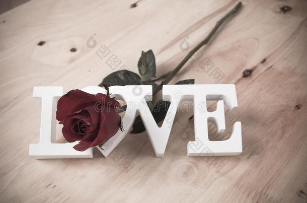 概念情人节，红玫瑰和测试爱情的棕色木制背景，复古色调