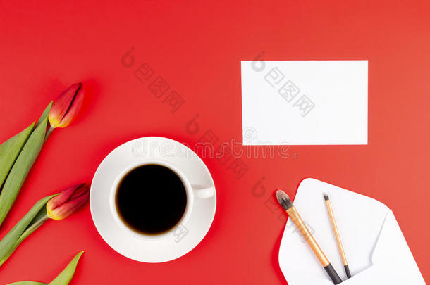 创意背景与化妆刷与信封，空白纸，咖啡杯和花在红色背景