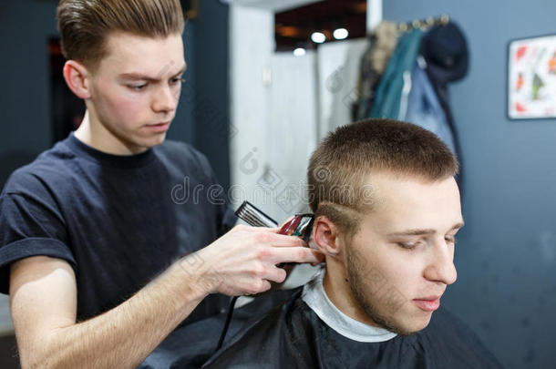 在理发店玩得很开心。 在理发店里坐在椅子上，快乐的小胡子男人被理发师理发