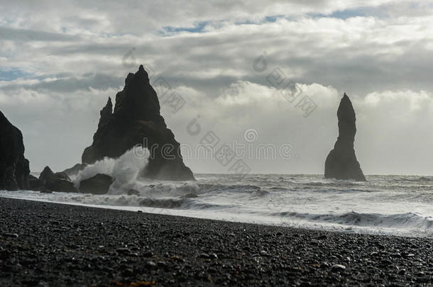 冰岛的黑沙滩雷尼斯法拉。 水里的岩石。 海浪和水溅成岩石。