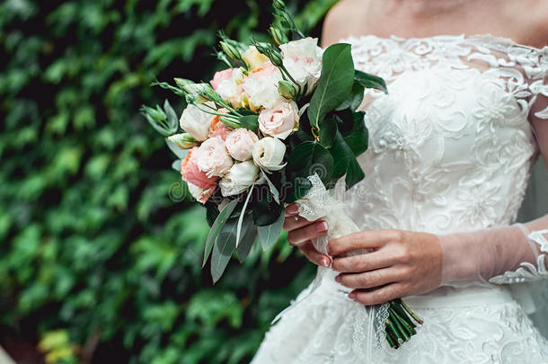新娘穿着一件豪华的婚纱，拿着一束玫瑰做的婚礼花束
