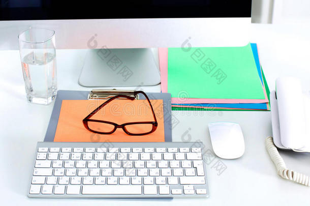 一本笔记本，笔记本电脑，钢笔，白纸文件放在办公桌<strong>后面</strong>的白色盲人桌子上
