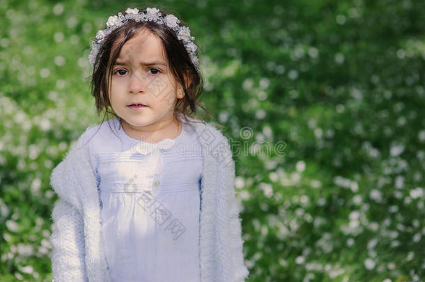 可爱的蹒跚学步的女孩穿着浅蓝色连衣裙，在盛开的春天花园里散步和玩耍